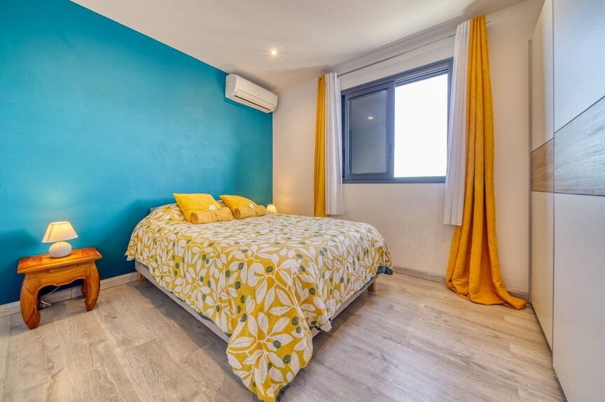 Chambre climatisée au mur bleu lagon et linge jaune – villa avec piscine chauffée à Saint-Pierre, La Réunion